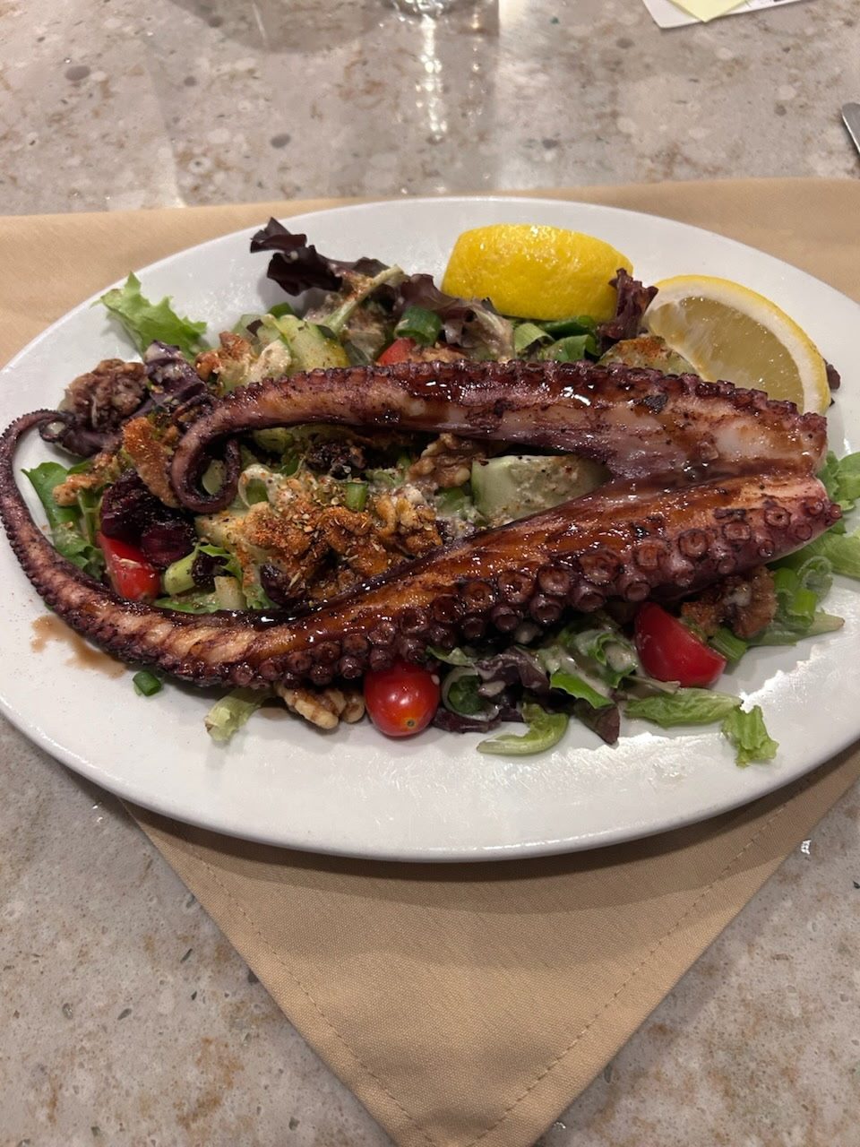 Grilled octopus over mixed greens with lemon
