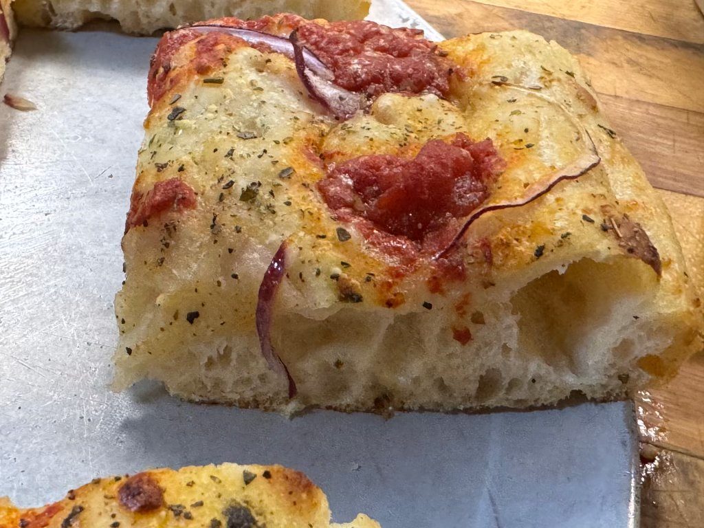Thick square pizza slice with tomato and red onion