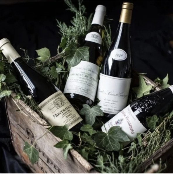 Wine bottles arranged in a wooden crate with greenery, from the supplied Village Vines image