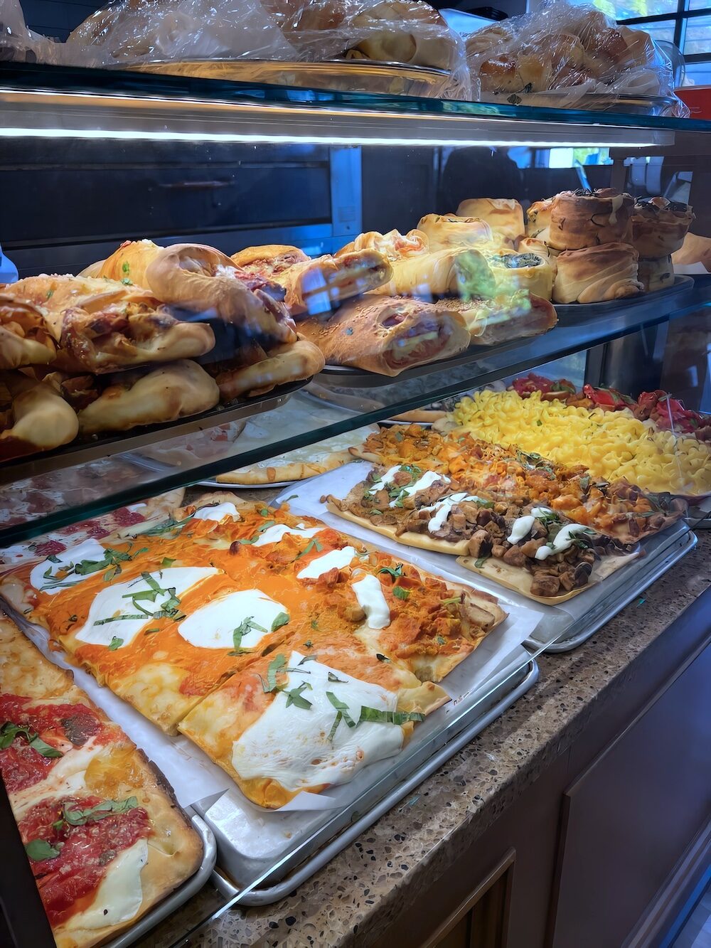 Square pies and rolls in Francesco’s pizzeria case
